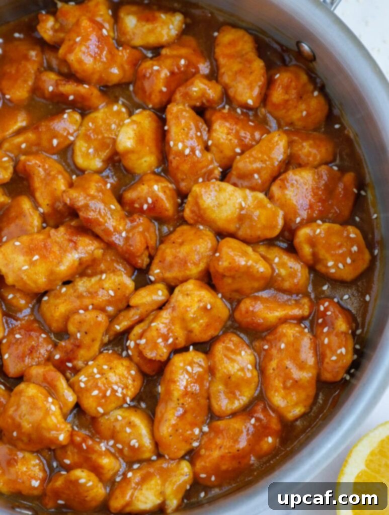 Wholesome Orange Chicken 11 A close-up of healthy orange chicken beautifully arranged in a pan, coated with a glossy sauce, ready to be served.