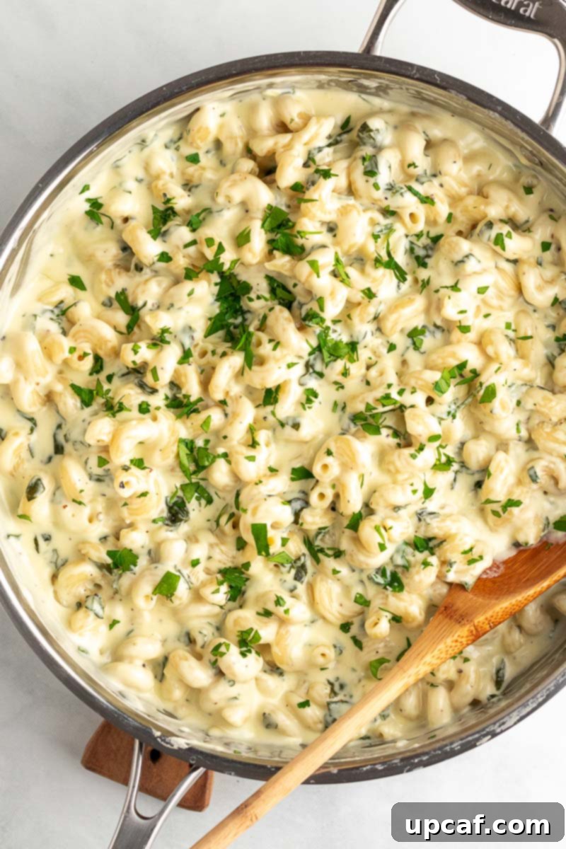 Overhead view of a skillet filled with vibrant green and white creamy spinach mac and cheese.