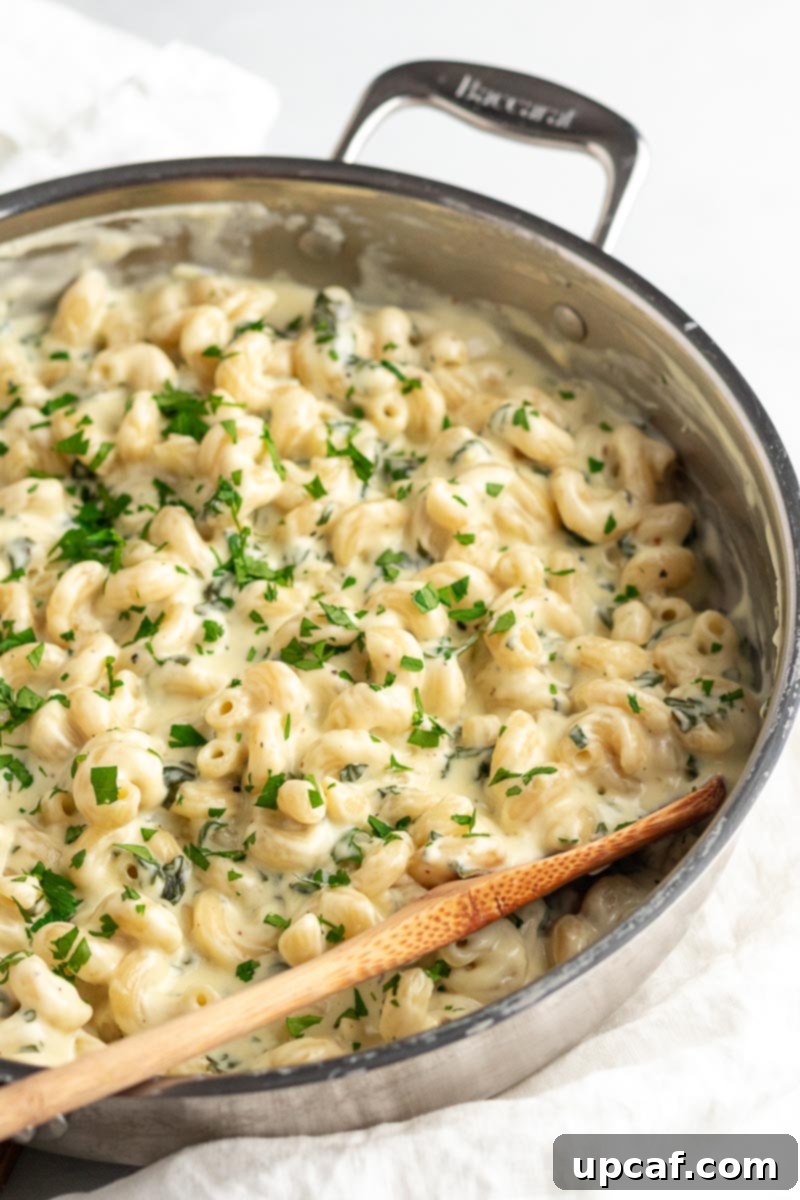 Side view of creamy spinach mac and cheese served in a skillet, showcasing its rich texture.