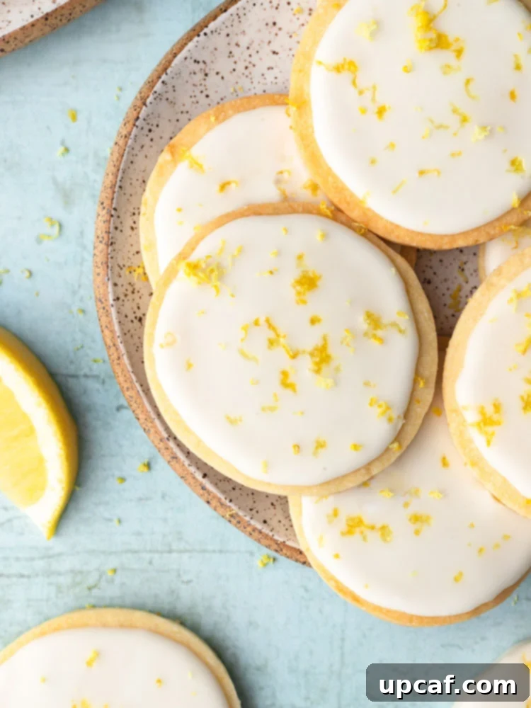 Tangy Lemon Glazed Shortbread 2 Top-down shot showing elegantly iced lemon shortbread cookies arranged on a plate with a soft blue background, highlighting their delicate crumb and citrusy glaze.
