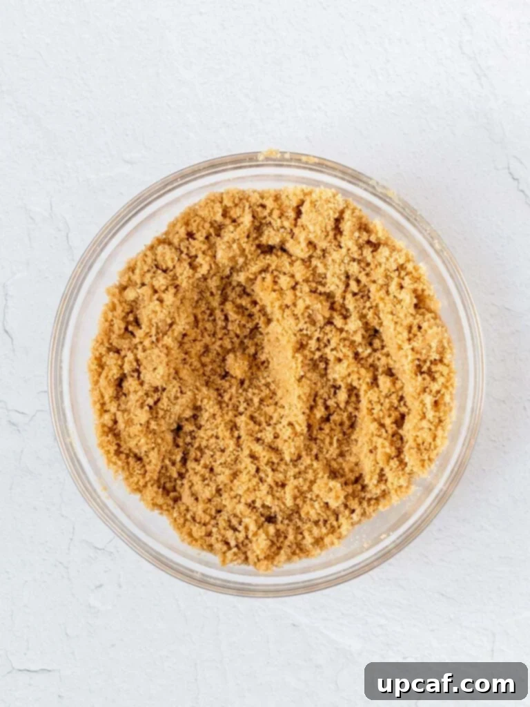 A bowl filled with finely crushed graham cracker crumbs, sugar, and melted butter, ready to be mixed for the pie crust.