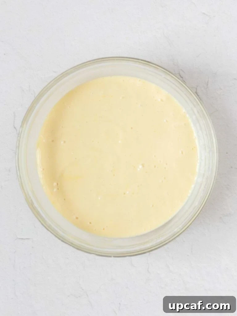 A bowl of luscious, pale yellow creamy lemon pie filling, perfectly mixed and ready to be poured into the prepared crust.