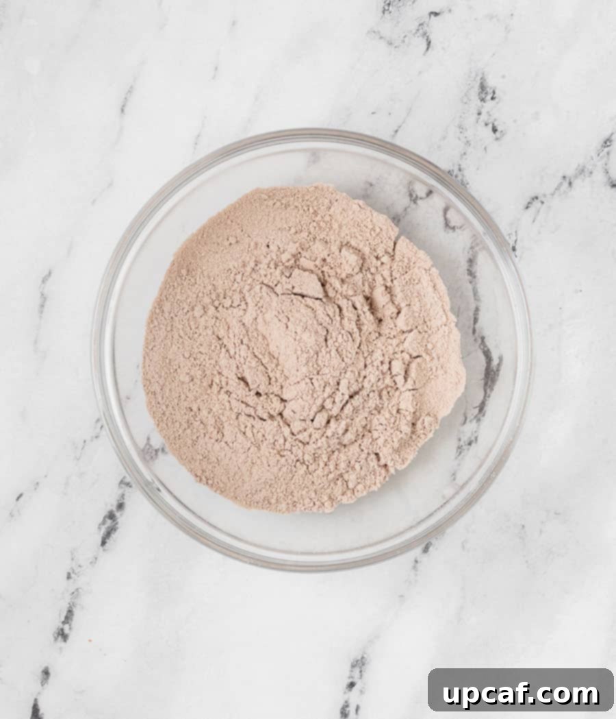 A bowl filled with finely sifted dry ingredients—powdered sugar, almond flour, and cocoa powder—perfectly mixed and lump-free, ready for the next stage of macaron preparation.