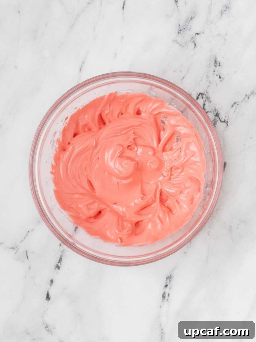 A vibrant red macaron batter, perfectly emulsified and glossy, showing stiff peaks in a mixing bowl, indicating it's ready for the macaronage process.