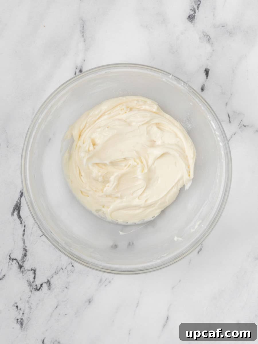 A bowl of rich, creamy, and fluffy white cream cheese filling, expertly prepared and ready to be piped into the red velvet macaron shells.