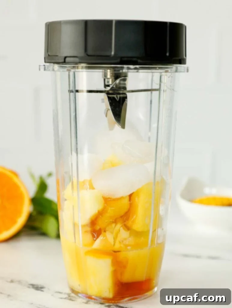 Pineapple slushie inside of a blender to be blended up.