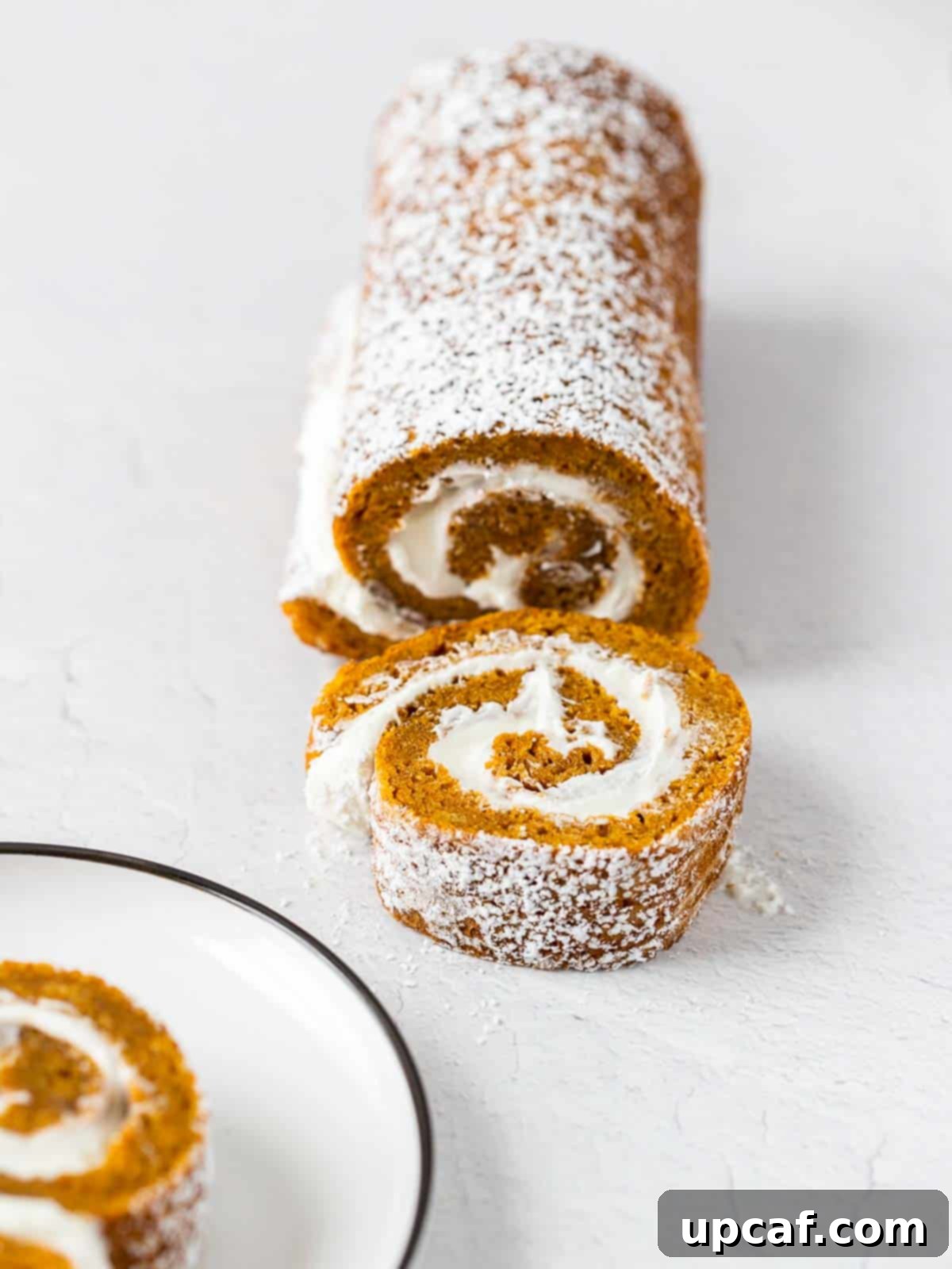 a beautifully presented pumpkin cake roll with a perfect slice cut out, showcasing the creamy filling