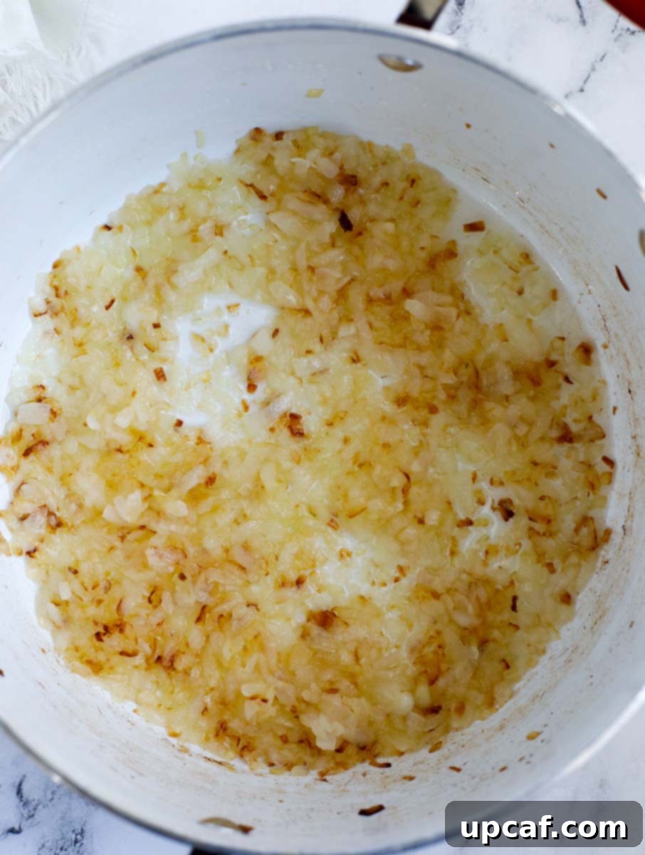 Hearty Lebanese Chicken Lentil Soup 4 Finely diced onions being sautéed in olive oil in a large pot, turning golden brown.