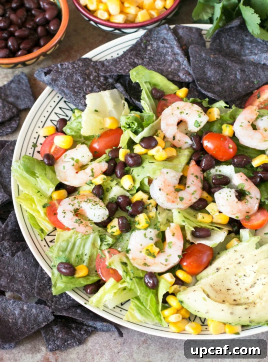 Mexican Shrimp Taco Salad served on a white plate, surrounded by blue corn tortilla chips