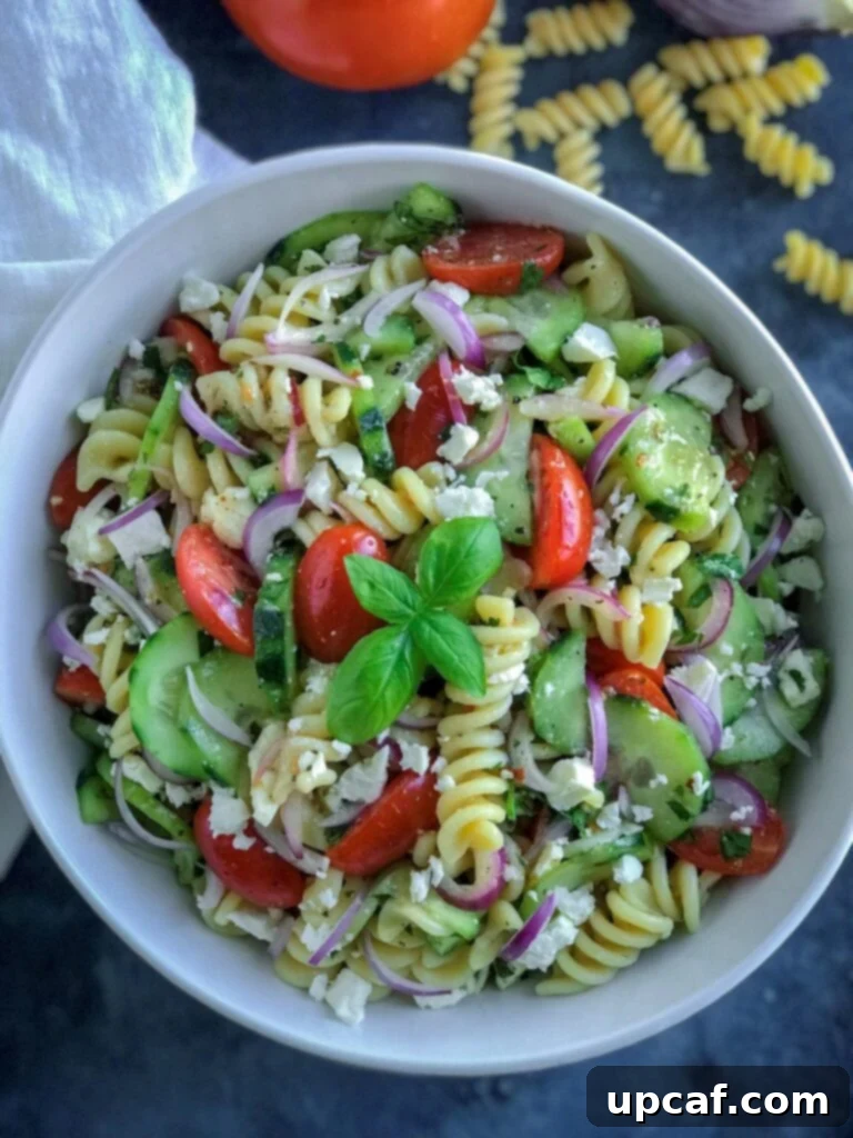 Vibrant Greek Pasta Salad 5 A large serving bowl filled with fresh Greek Pasta Salad, garnished with extra feta and parsley, ready to be enjoyed.