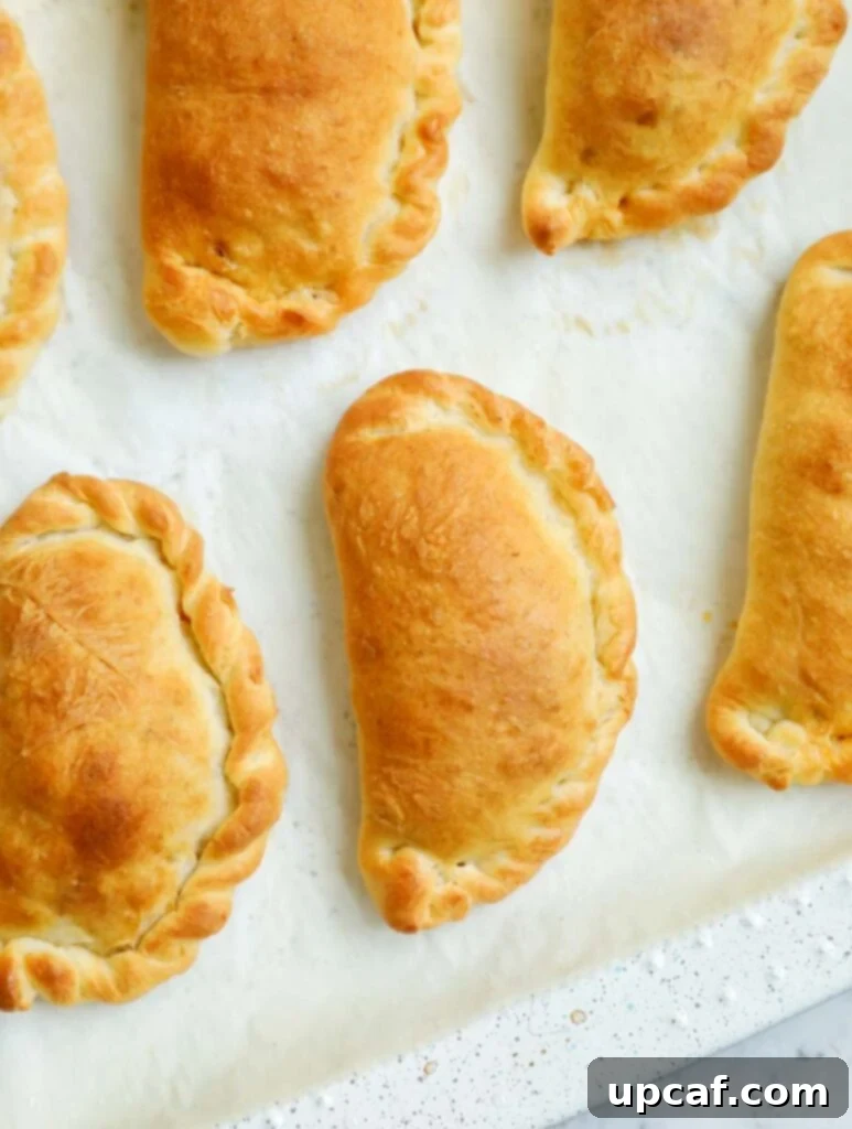 Freshly baked Lebanese meat pies arranged on a parchment-lined baking sheet.