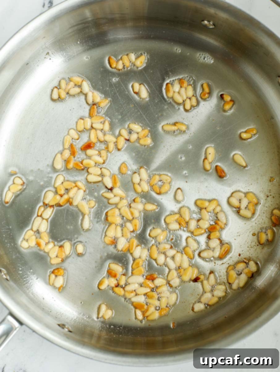 Pine nuts being fried in a pan until golden brown and fragrant.
