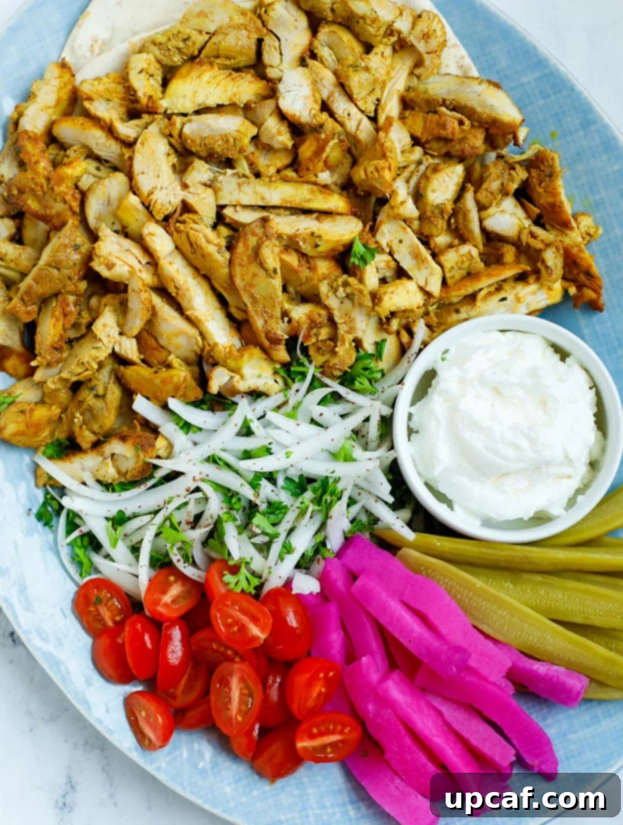 A platter of chicken shawarma with dip and sides, inviting and delicious.