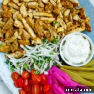 A platter of chicken shawarma with dip and sides.
