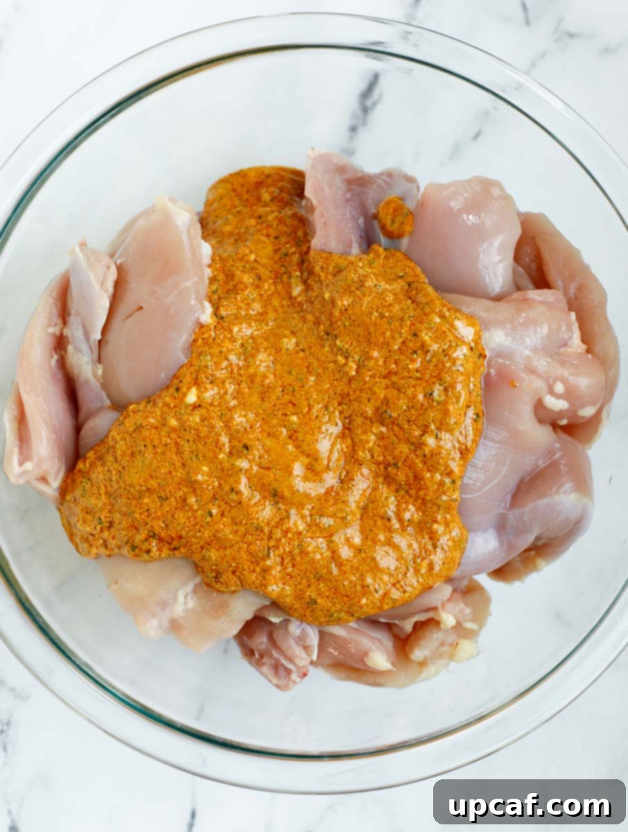 Marinade poured over top of chicken thighs before and after mixing together, showing the rich color.