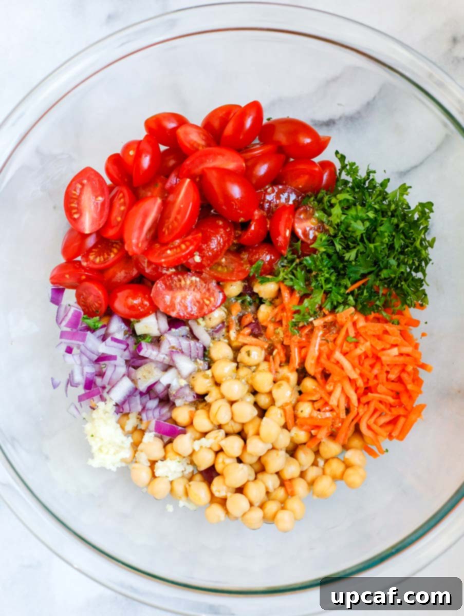 Large bowl with tomatoes, herbs, carrots, chickpeas, onions, and garlic, waiting for spinach.