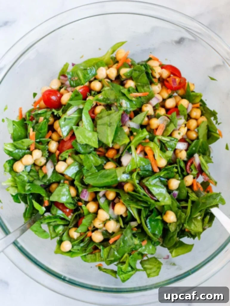 A large bowl of freshly tossed spinach chickpea salad, ready to be served.