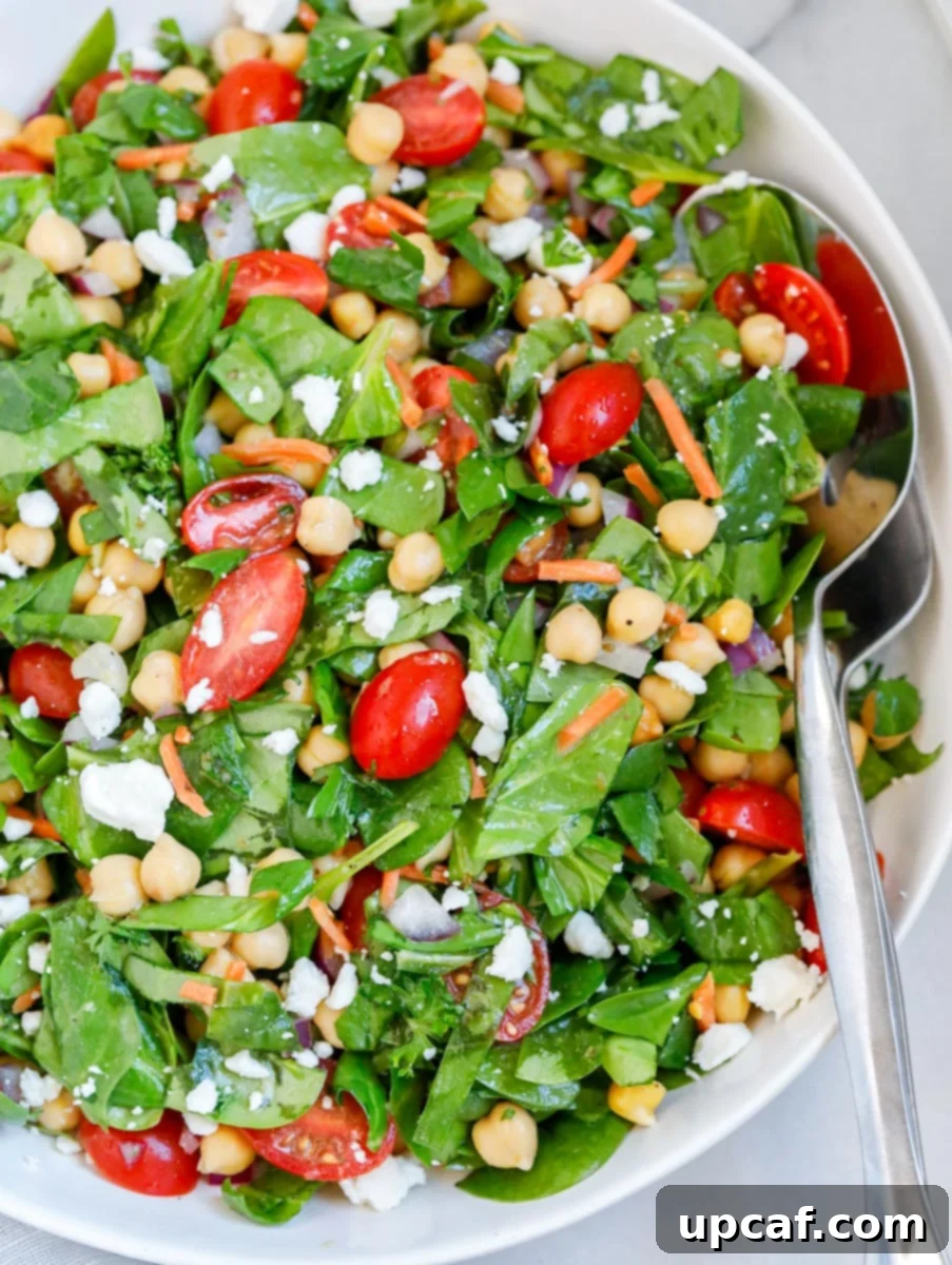 Close up view of an easy chickpea spinach salad, showing fresh ingredients and dressing.