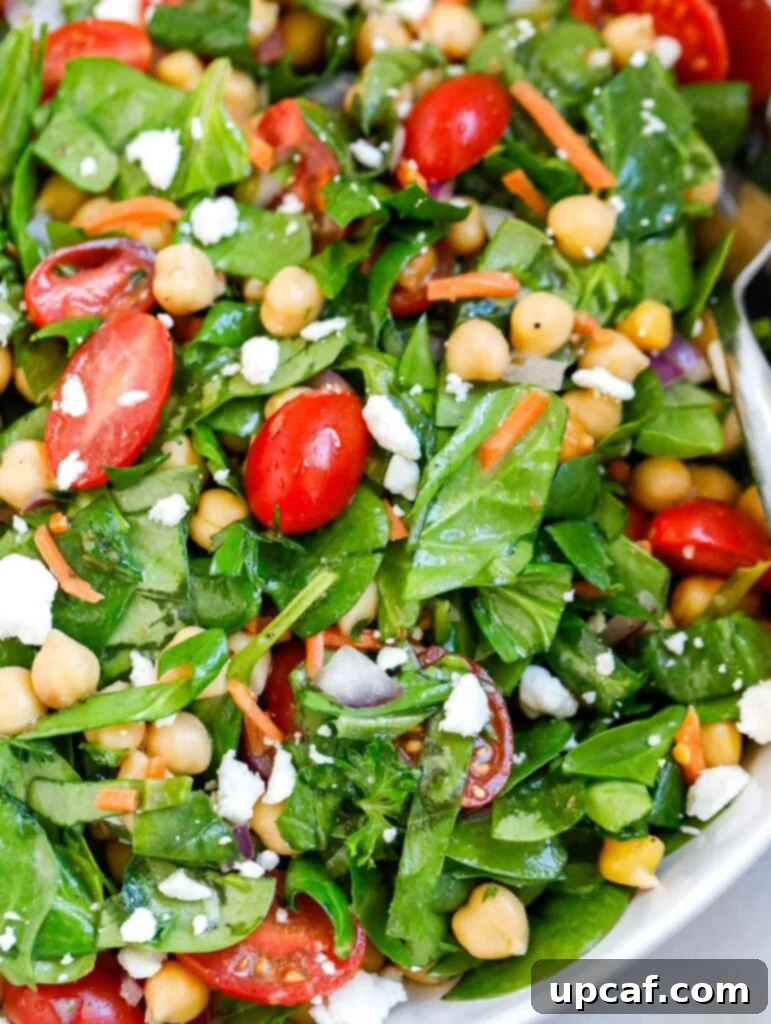 Close up shot of a vibrant chickpea spinach salad in a bowl, showing texture and freshness.