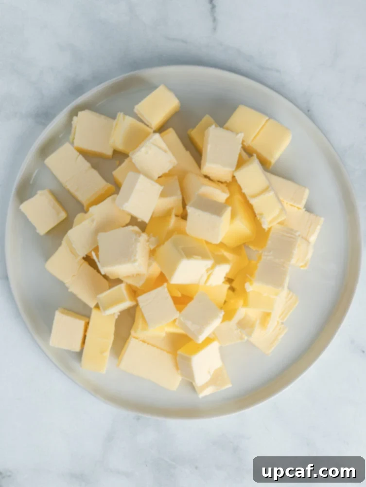 Cubed unsalted butter on a plate, ready for ghee preparation.