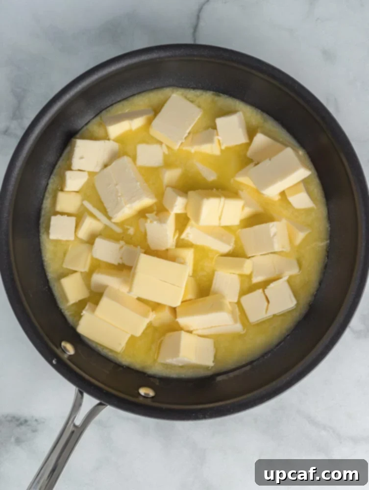 Unsalted butter melting in a saucepan over low heat.