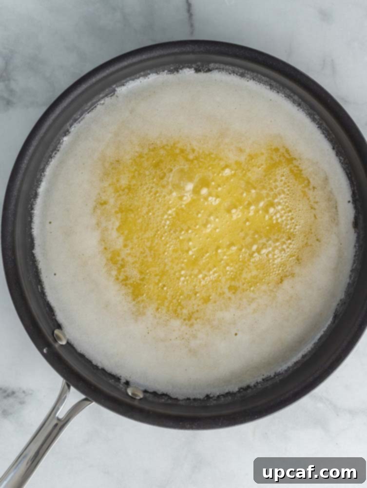 Melted butter simmering gently, with foam beginning to form on the surface.