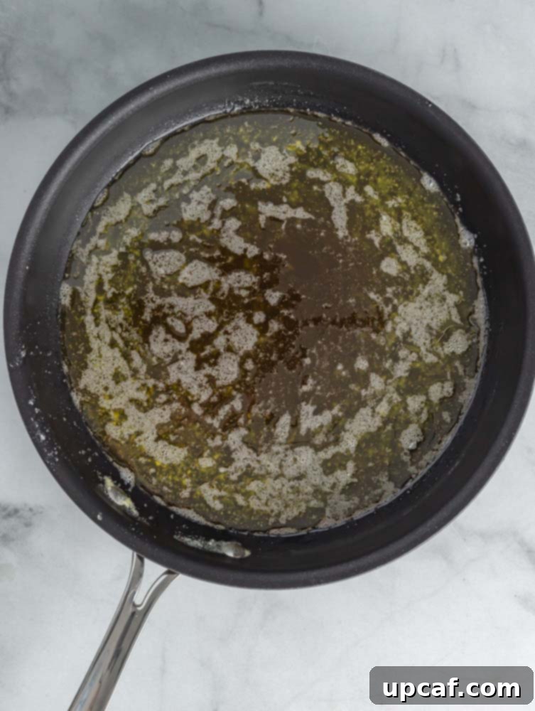 Ghee in a pan with clear golden liquid and browned milk solids settled at the bottom.