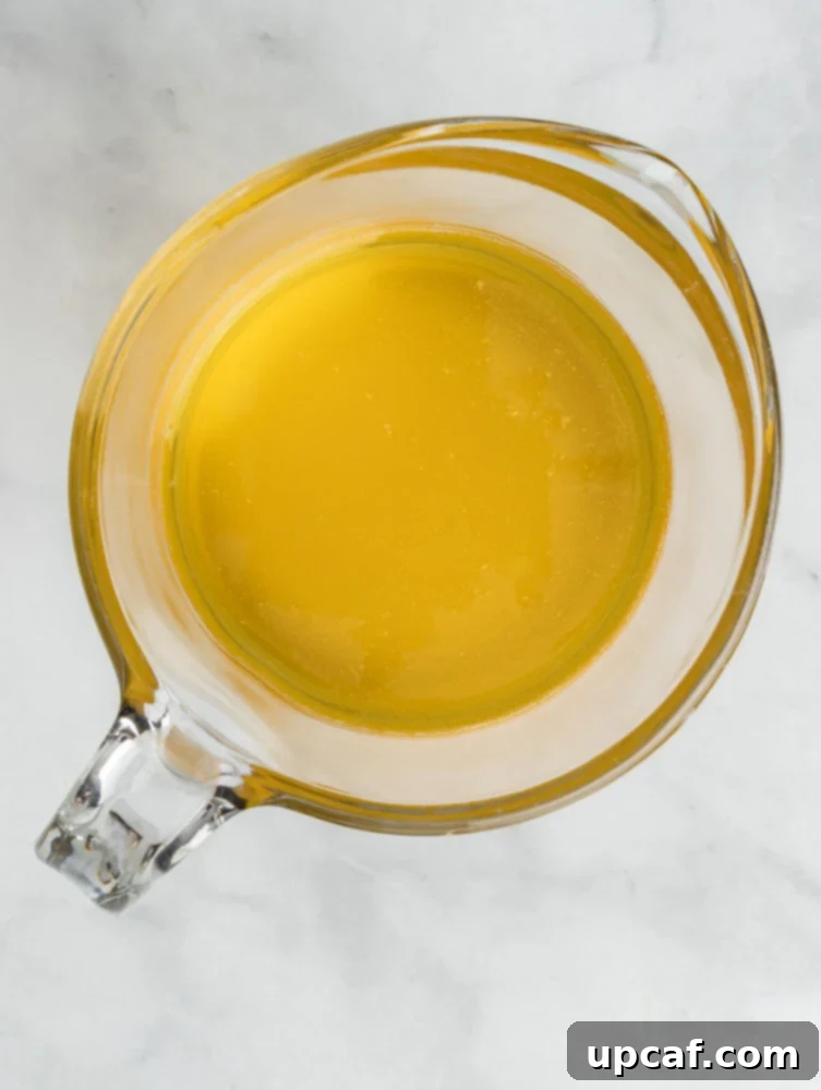 An overhead view of golden, translucent ghee in a clear measuring cup, showing its purity.