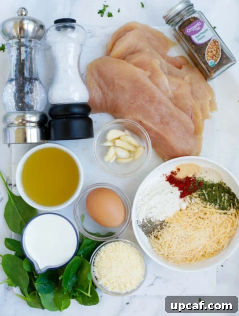 A curated selection of fresh ingredients laid out for making creamy parmesan chicken, including chicken, herbs, cheese, and cream.