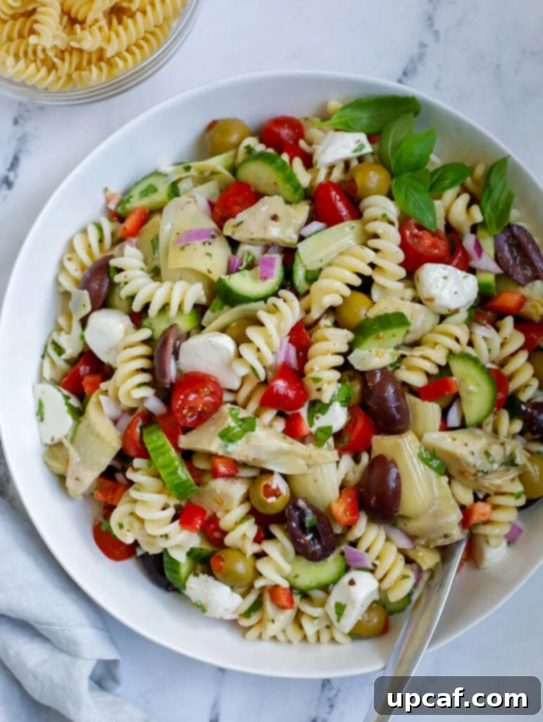 Vibrant Mediterranean Pasta Salad 2 A vibrant Mediterranean pasta salad served in a large white bowl, garnished with fresh herbs, showcasing a mix of pasta, cherry tomatoes, olives, and cheese.