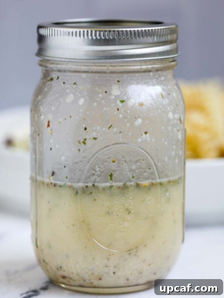 Vibrant Mediterranean Pasta Salad 4 Homemade Greek dressing in a mason jar, showcasing its vibrant color and fresh ingredients.