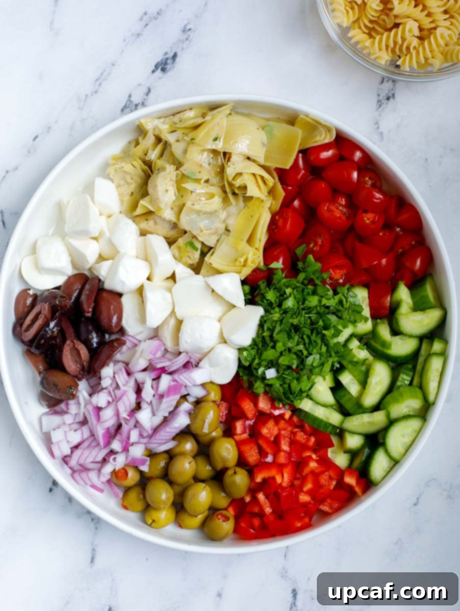 Vibrant Mediterranean Pasta Salad 5 A large bowl filled with an assortment of freshly chopped vegetables including tomatoes, cucumbers, olives, and bell peppers, ready to be mixed for the pasta salad.
