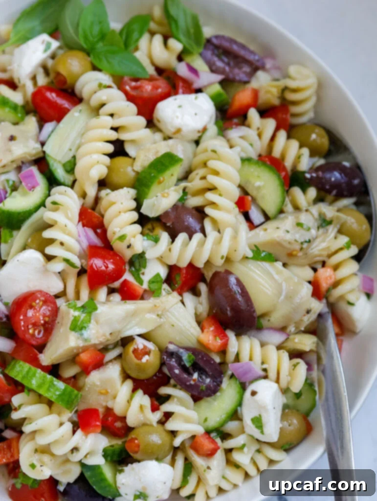 Vibrant Mediterranean Pasta Salad 8 A close-up view of the finished Mediterranean pasta salad in a large bowl, showing the texture and vibrant colors of the ingredients.