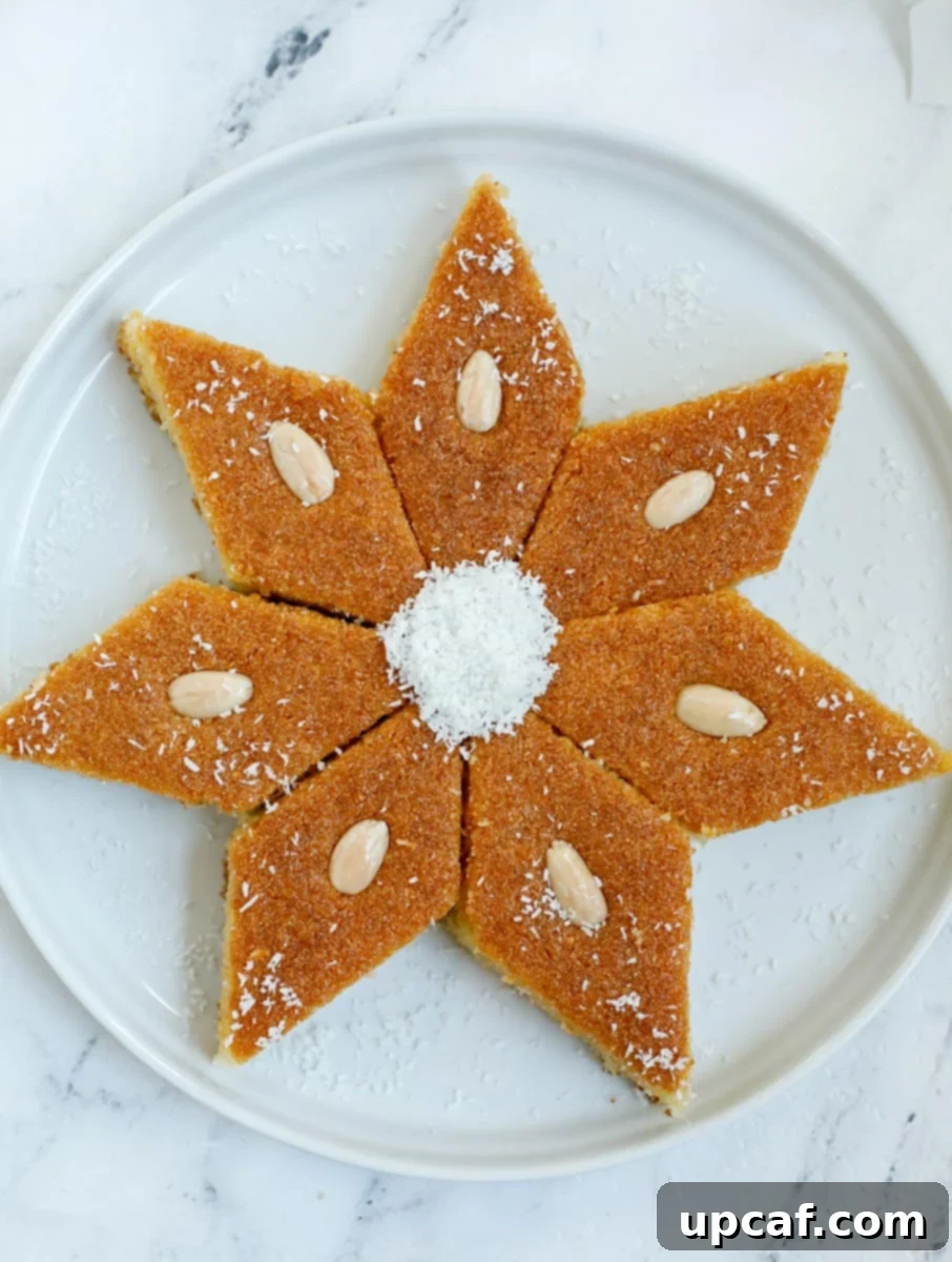 Seven perfectly cut pieces of Coconut Basbousa, each topped with an almond, arranged in a star shape on a white platter.
