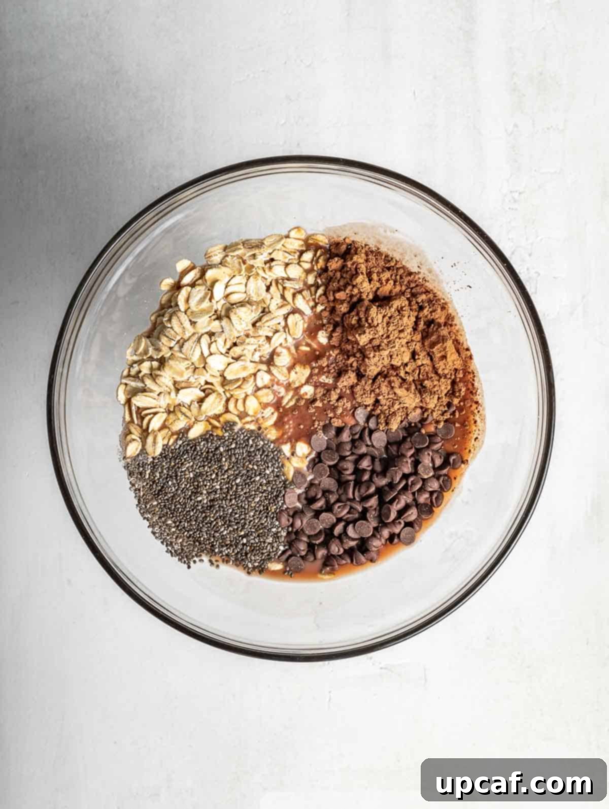 A bowl filled with dry ingredients for chocolate overnight oats, including oats, cocoa powder, and chia seeds, before liquids are added.