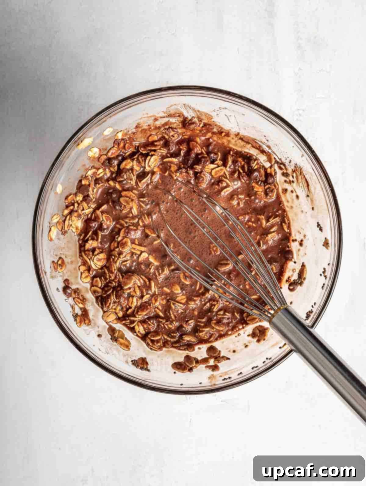 The chocolate oats mixture in a bowl after all liquid ingredients have been added and stirred, showing a smooth, consistent blend.