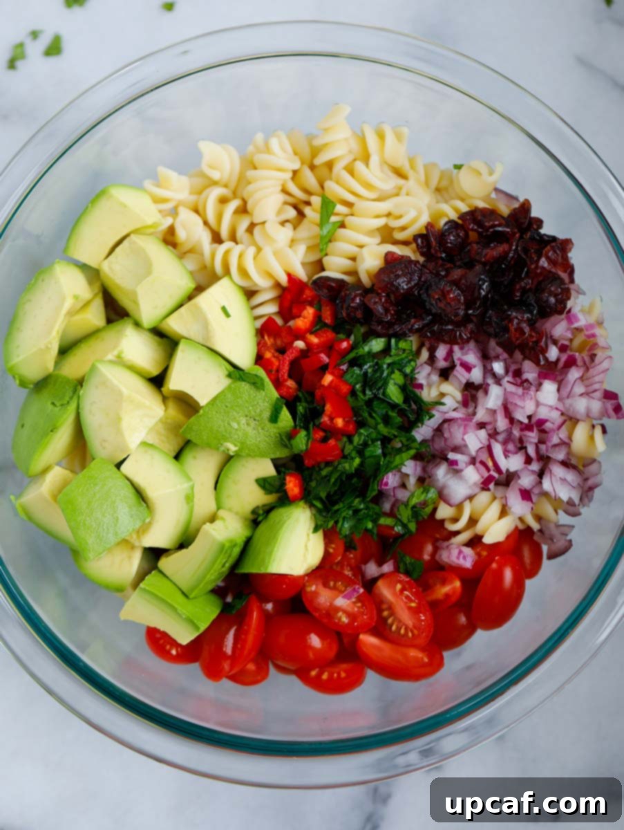 Chopped ingredients for avocado chicken pasta salad in a large mixing bowl, ready for dressing.
