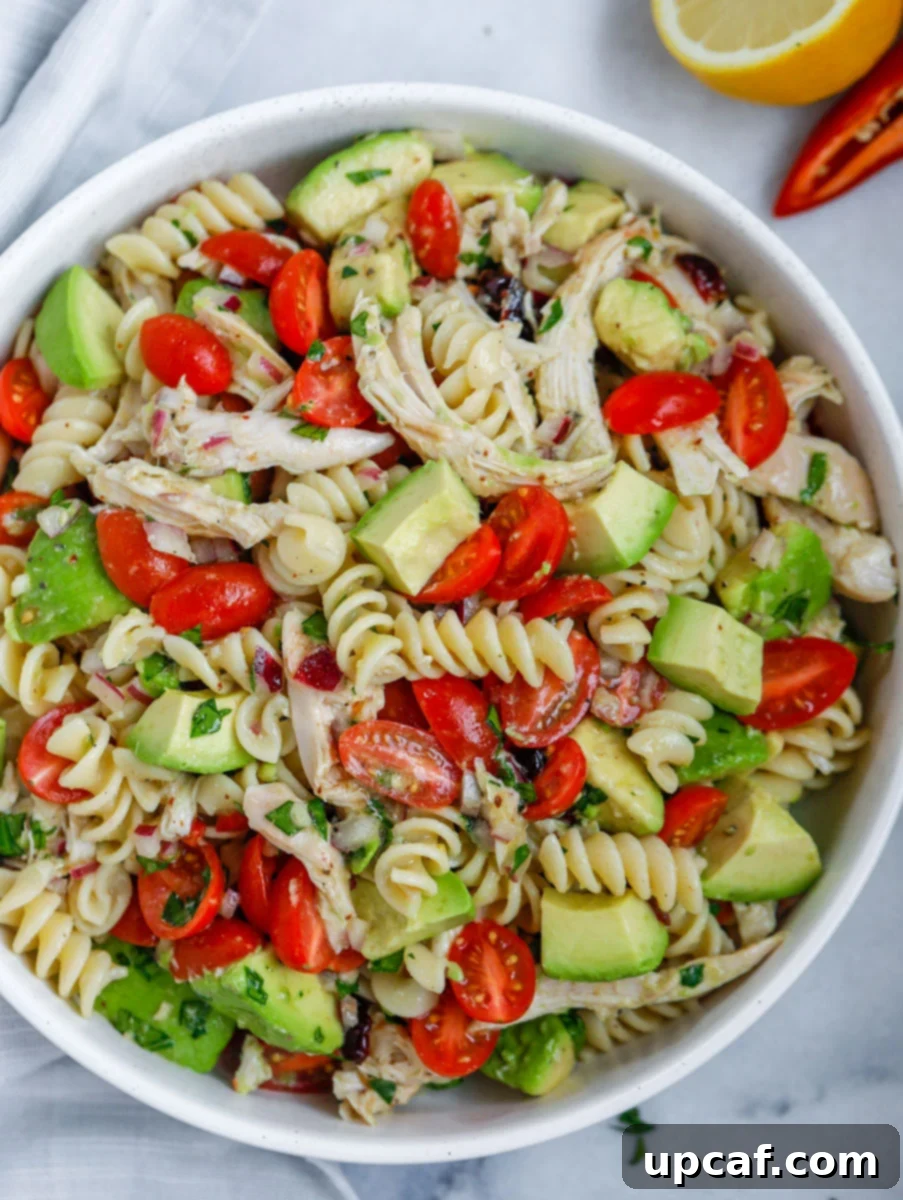 A wide shot of a large bowl of fresh avocado chicken pasta salad, beautifully presented.