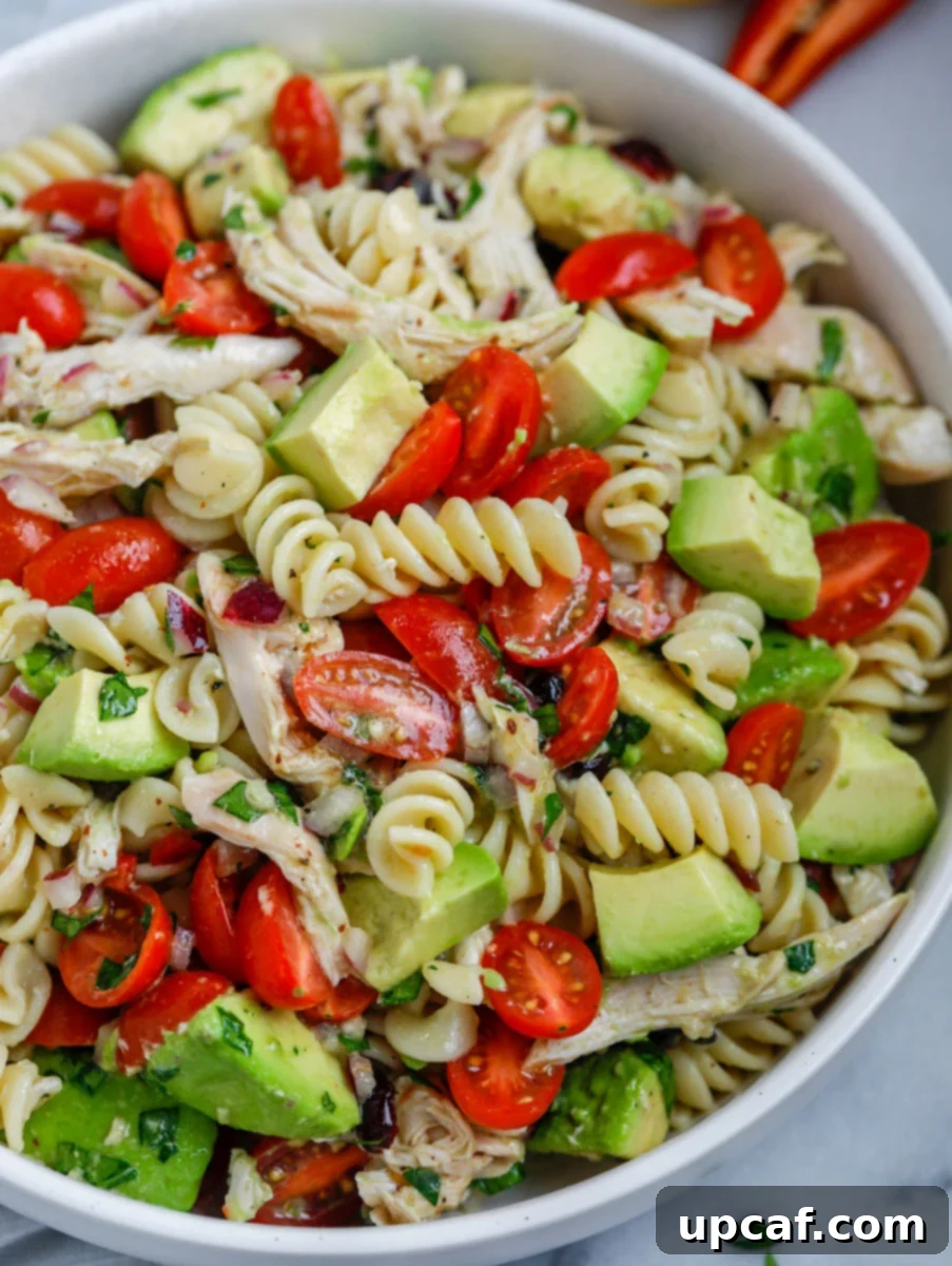 A close-up of a portion of avocado chicken pasta salad, highlighting the creamy avocado and tender chicken.