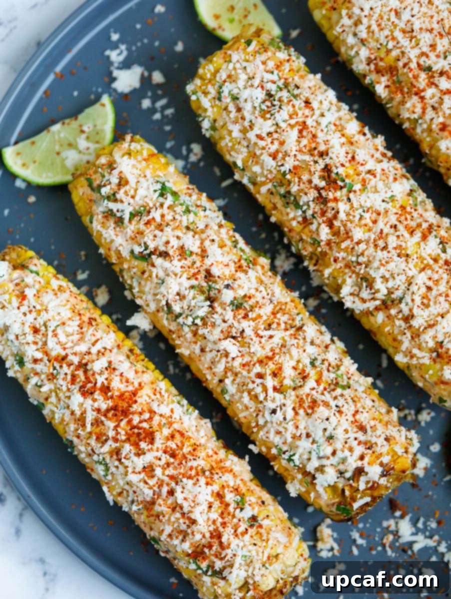 Authentic Mexican Elote 12 Close-up of fully loaded Mexican street corn on a plate, showcasing abundant cheese and sauce.