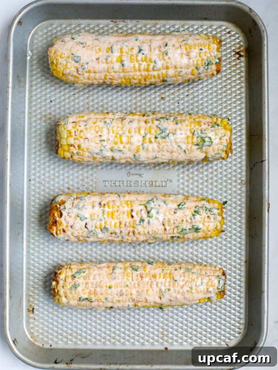 Authentic Mexican Elote 9 Grilled corn on the cob being generously brushed with the prepared Mexican street corn sauce.