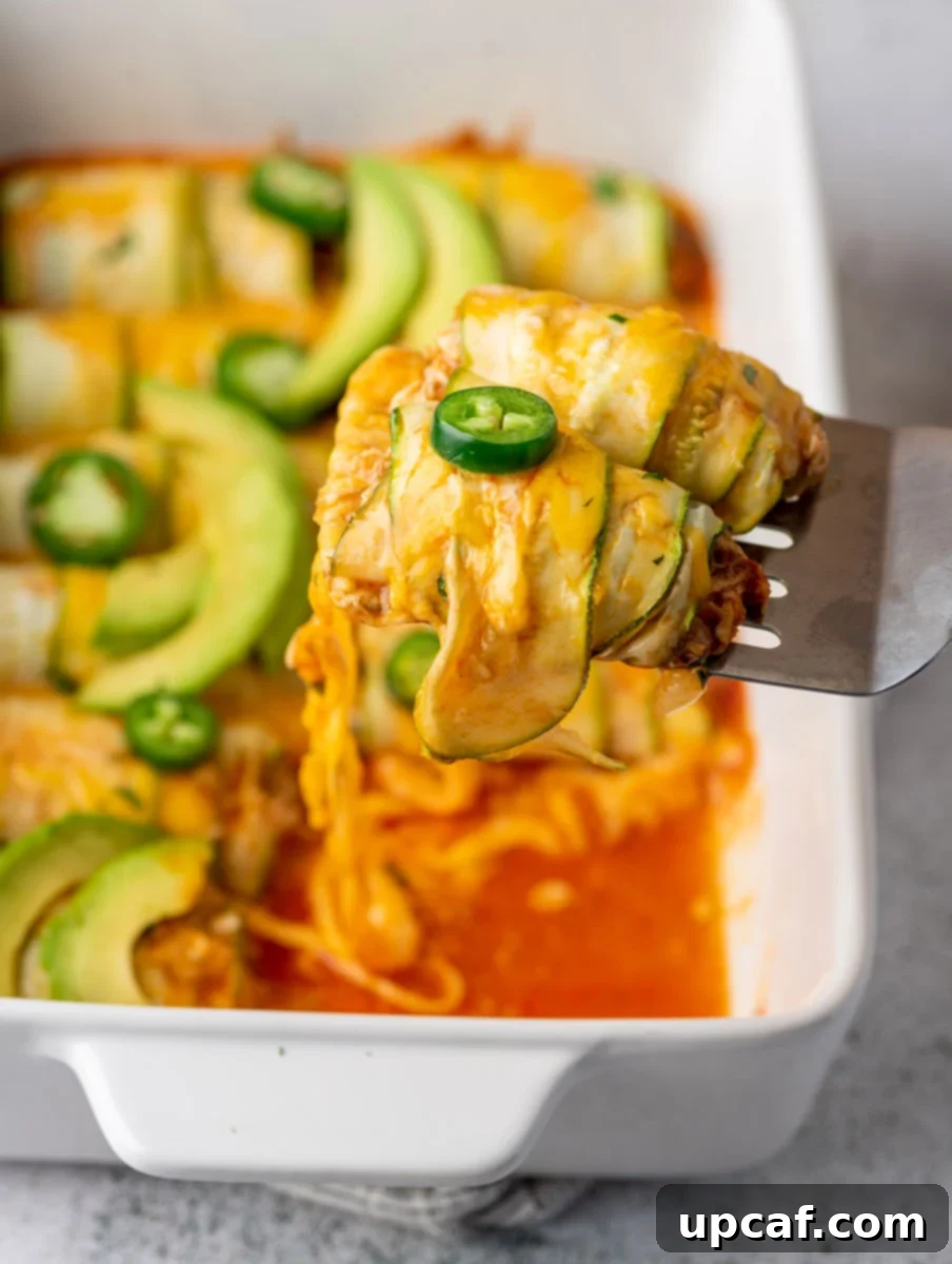 Southwest Chicken Zucchini Enchiladas 2 A generous scoop of Chicken Zucchini Enchilada casserole, showcasing the layers of chicken, sauce, and melted cheese, with fresh cilantro garnish.
