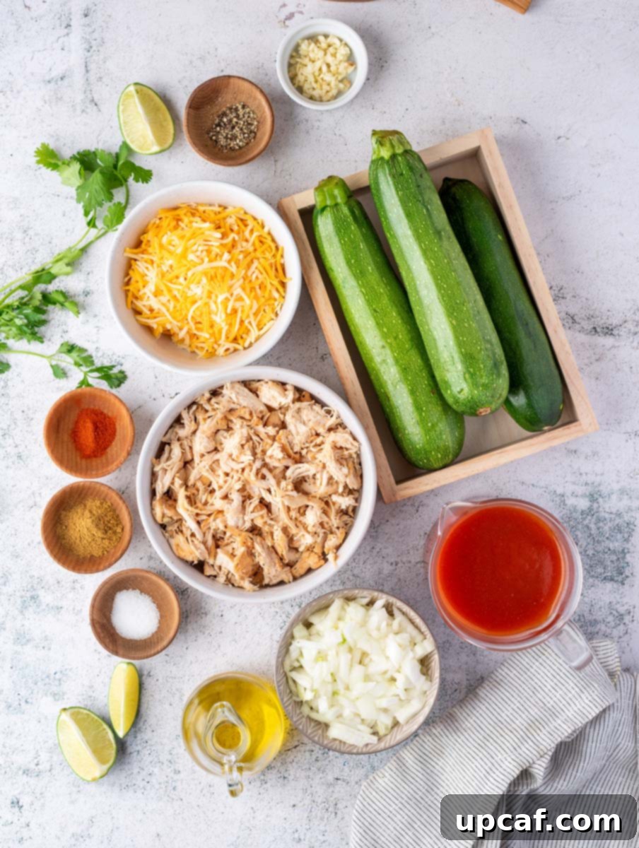 Southwest Chicken Zucchini Enchiladas 3 Assortment of fresh ingredients laid out, including olive oil, garlic, onions, spices, shredded chicken, enchilada sauce, lime, zucchini, Mexican style cheese, jalapenos, and cilantro.