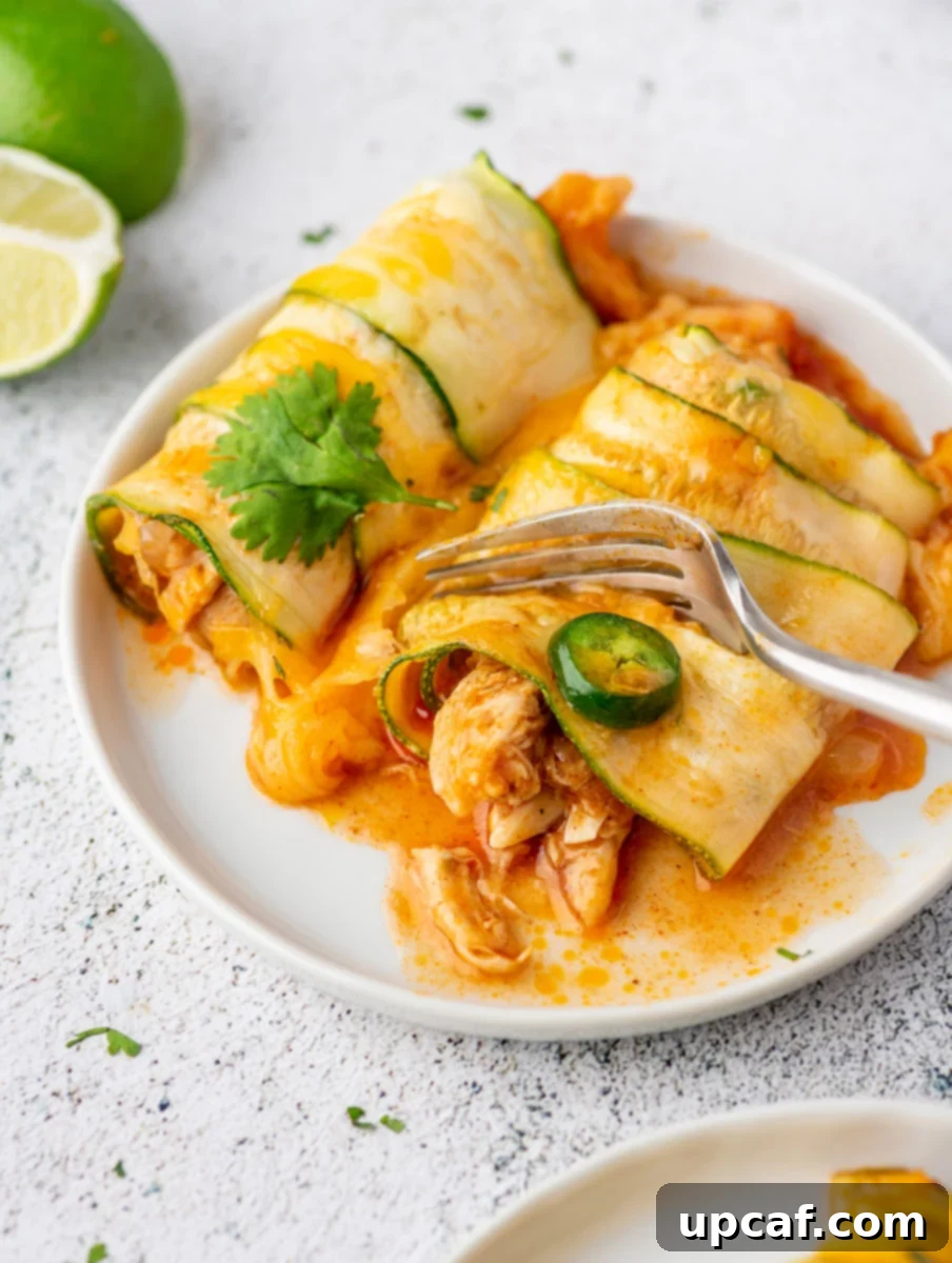 Southwest Chicken Zucchini Enchiladas 8 A fork cutting into a piece of golden-brown chicken zucchini enchilada, showing the rich filling and melted cheese.