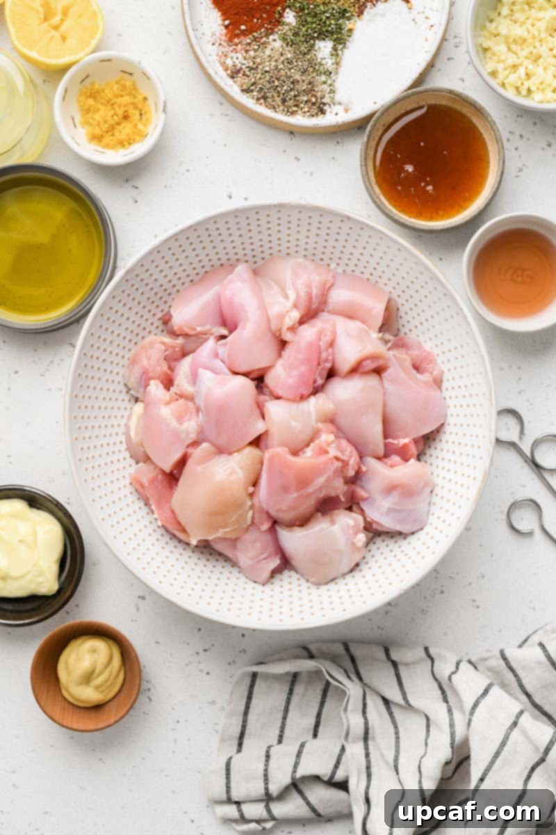 Close-up, top-down view of raw chicken chunks marinating in lemon garlic sauce in a glass bowl.