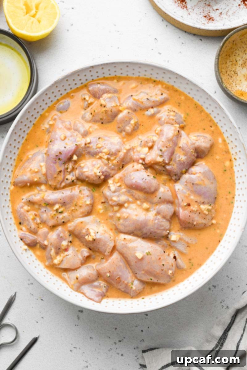 Close-up shot of chicken marinated in the lemon garlic sauce in a bowl, ready for skewering.