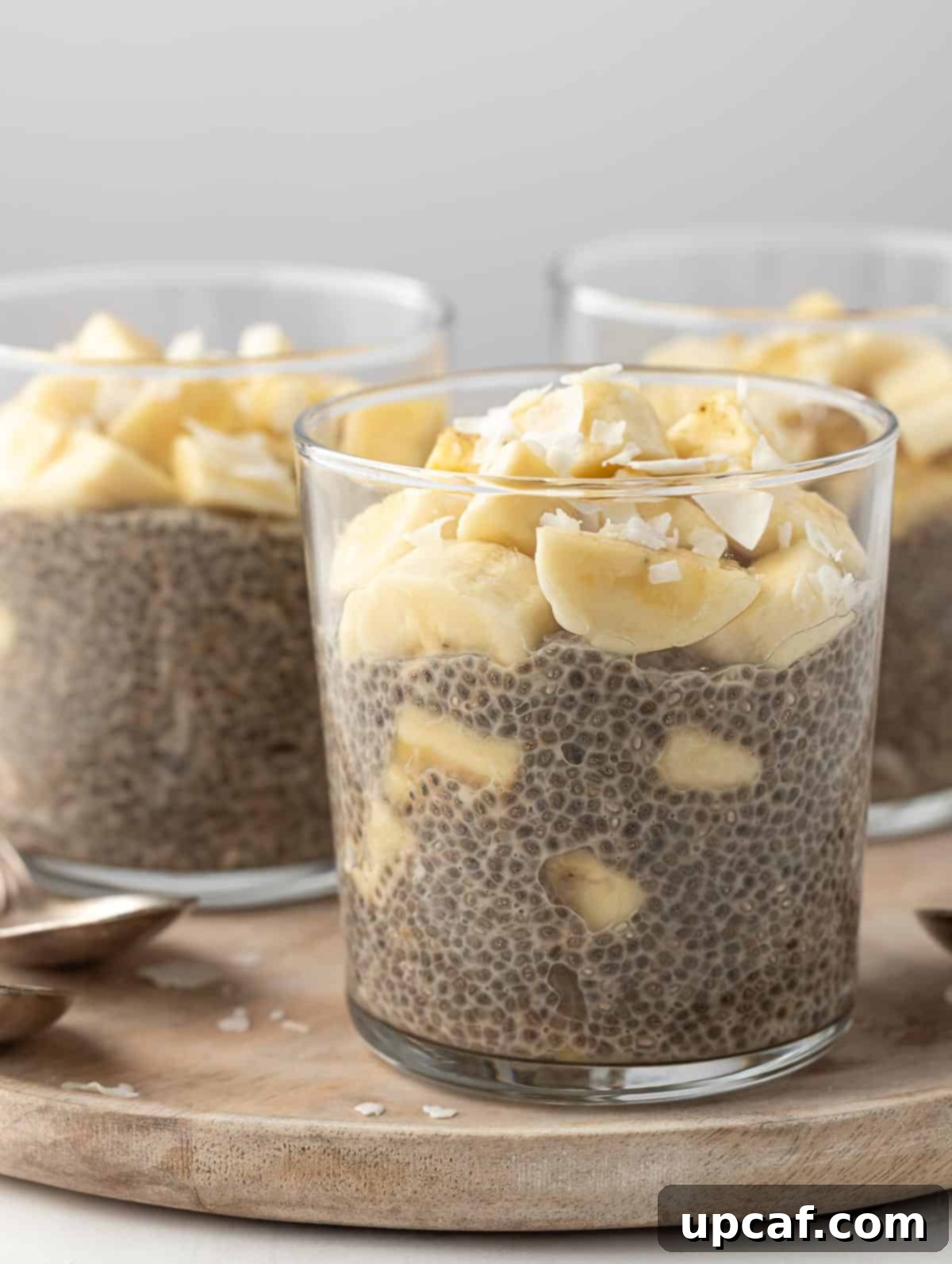 close up shot of a cup of banana cream pie protein chia pudding, showing layers and toppings