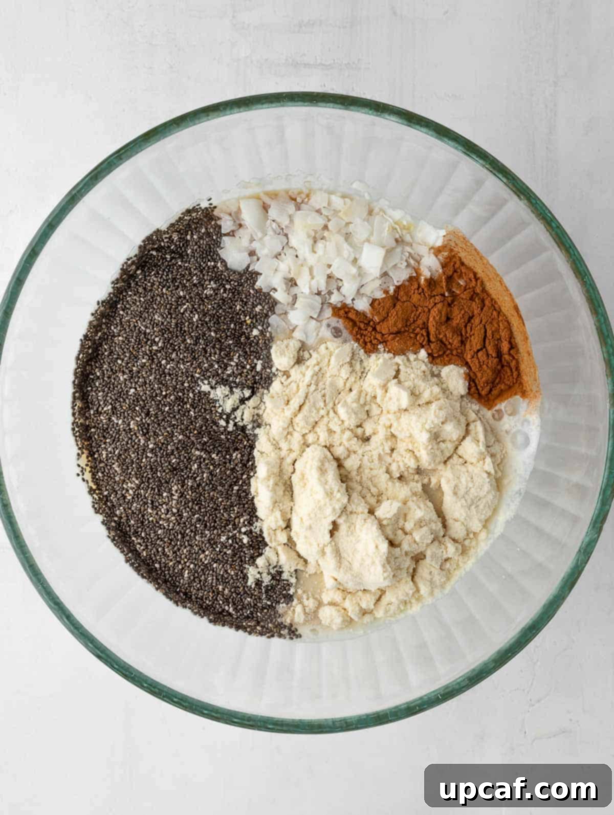 all the dry and wet ingredients of the protein chia pudding being mixed in a bowl