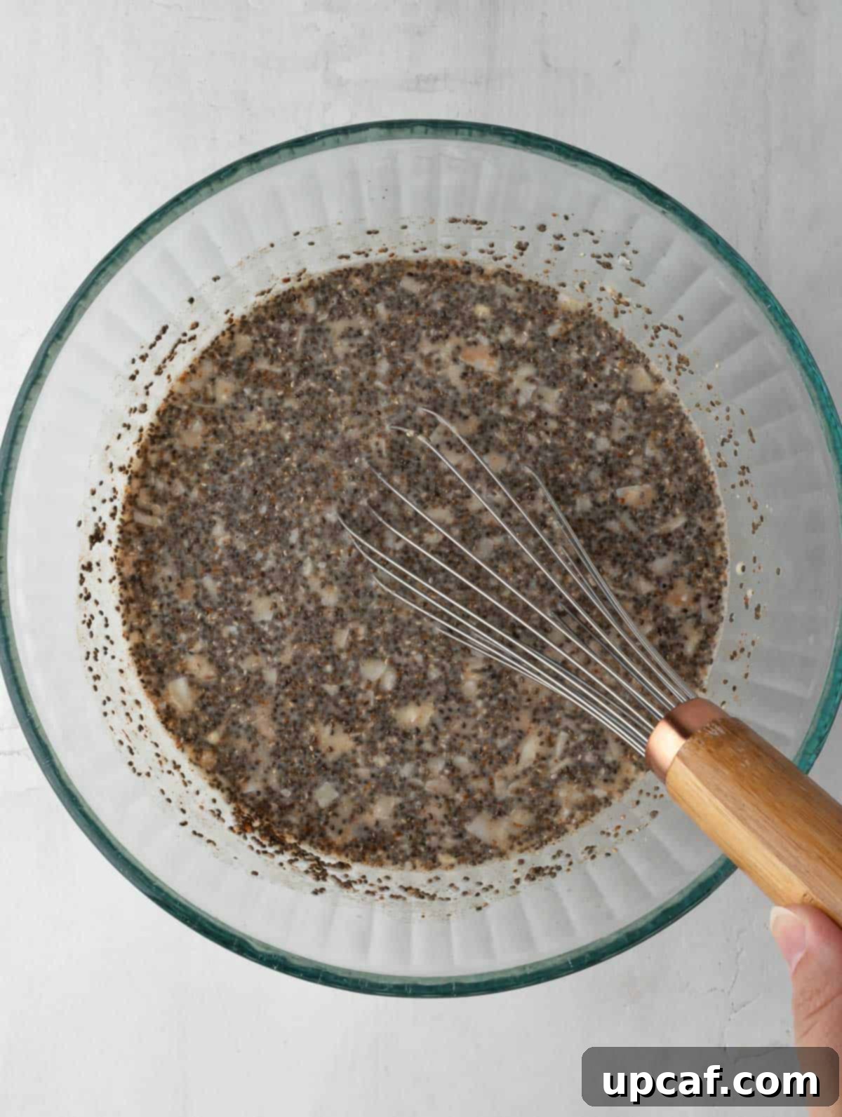 chia seeds being mixed into a liquid in a clear bowl, showing the thickening process