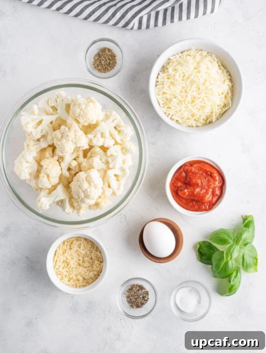 Neatly arranged ingredients for cauliflower pizza, including fresh cauliflower, eggs, cheese, spices, and sauce.